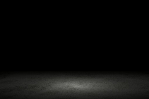 Light shining down on black marble floor in dark room with copy space, abstract background