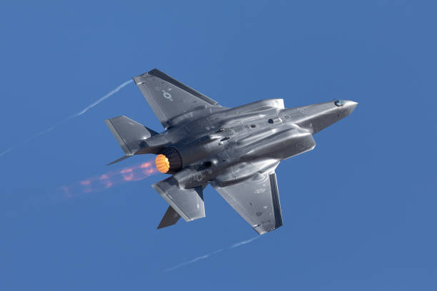 f-35 lightning ii in a high-g maneuver, with afterburner on and condensation trails at the wing’s tips - f 35 imagens e fotografias de stock