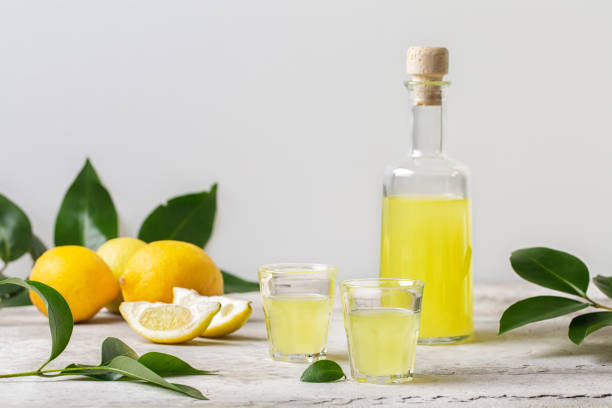 Limoncello in small glasses and bottle  - italian lemon liqueur, fresh italian lemons. Light background, copy space. stock photo