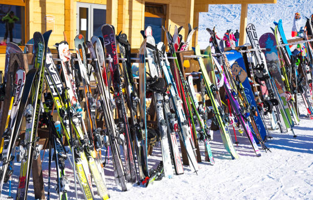 raden av skidor och snowboards lagras på rack utanför ett kafé på skidbackarna.  personer som softa i café efter acvite sport - skidled bildbanksfoton och bilder