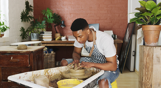 Shot of a young man working with clay in a pottery studio