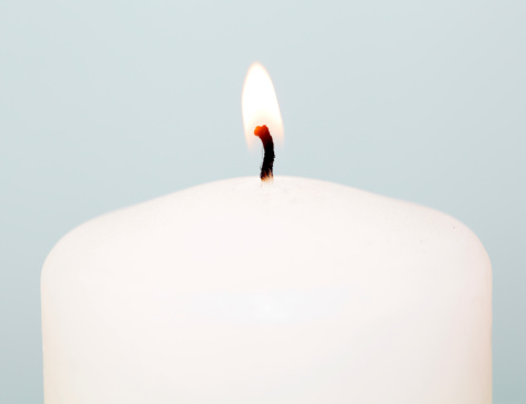 Macro of a large lit white candle.