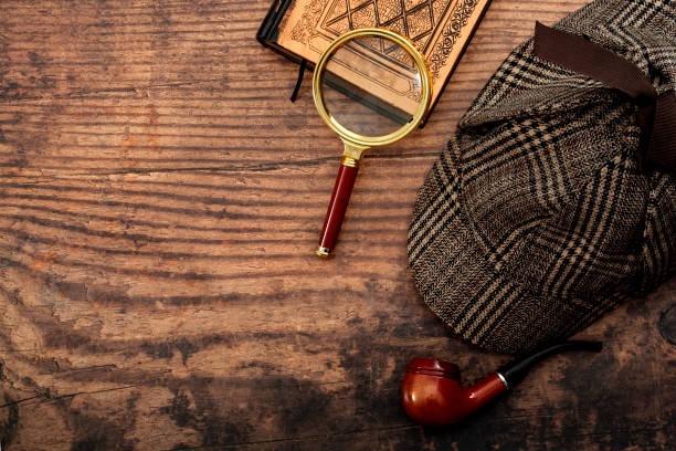 文学小説、シャーロックホームズ探偵帽子、喫煙パイプ、レトロな虫眼鏡とコピースペースを持つ木製のテーブルの上に隔離された古い本で犯罪と謎の物語の概念的なアイデアを調査 - 秘密 ストックフォトと画像