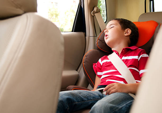 Litle boy sleeps in safe chair car stock photo