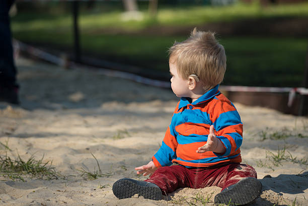 Littl boy with hearing aid at playground stock photo