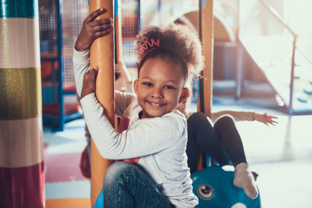 Little African American Girl Riding Carousel Little African American Girl Riding Carousel. Adorable Happy Children having Fun Together on Modern Indoor Playground. Amusement Center. Entertainment and Childhood Concept. Cheerful Kids. indoor playground stock pictures, royalty-free photos & images