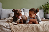 istock Little African American Girl with Dog on Bed 1361312102