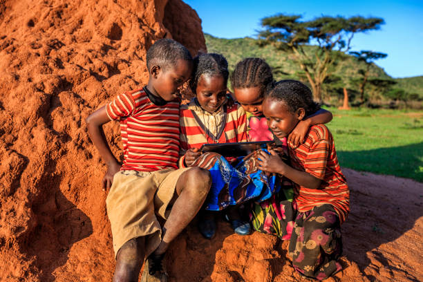 Little African children using digital tablet, East Africa Little African children using digital tablet in the village in Southern Ethiopia, Africa. Children are sitting on termite's mound. developing countries stock pictures, royalty-free photos & images