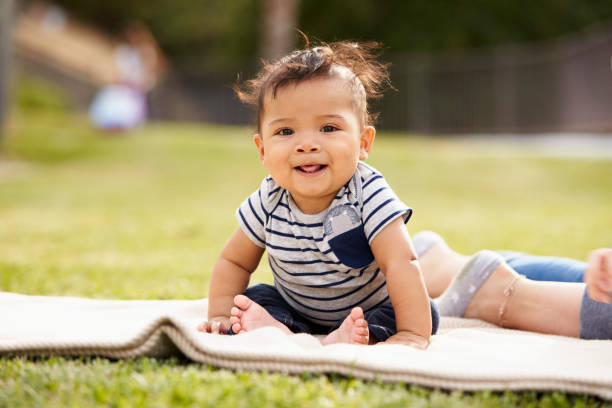 Little baby boy sitting up on a blanket in the park looking to camera, close up Little baby boy sitting up on a blanket in the park looking to camera, close up baby boys stock pictures, royalty-free photos & images