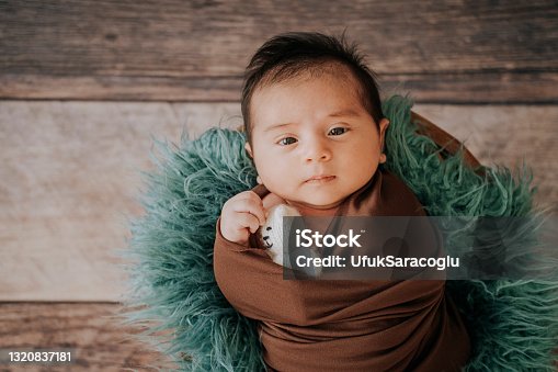 istock Little baby boy with knitted hat in a basket, happily smiling and looking at camera, isolated studio shot 1320837181
