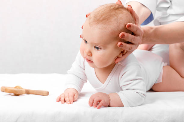Little baby receiving osteopathic treatment of head and neck stock photo