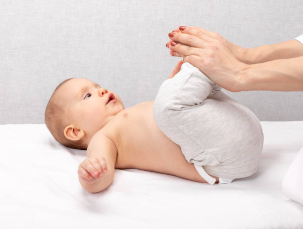 Little baby receiving osteopathic treatment of her leg to prevent hip dysplasia by pediatric physiotherapist stock photo