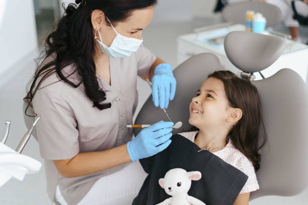 Little beautiful girl at the dentist smiling Cute little girl sitting on a modern dental chair and having dental consultation with dentist dentist stock pictures, royalty-free photos & images