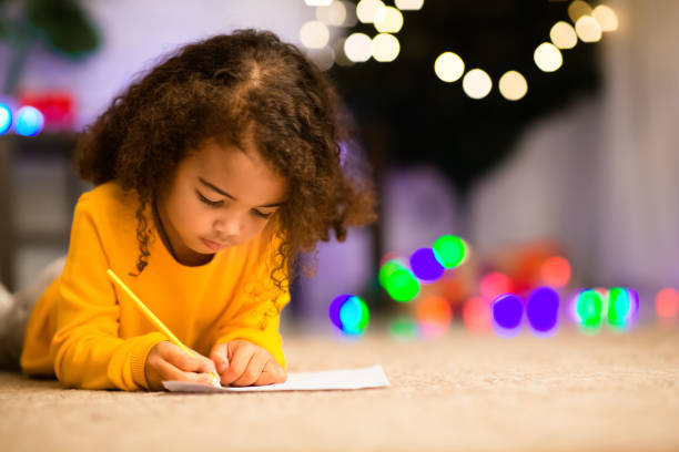 little black girl drawing on floor near xmas tree - a letter to santa claus, christmas gifts imagens e fotografias de stock