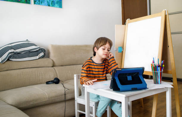 Little boy attending online classes from home. Tired and bored by home schooling. stock photo