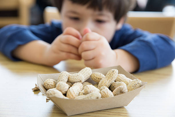 Little boy eating peanuts Little boy opening up peanuts to eat in a restaurant nut food stock pictures, royalty-free photos & images
