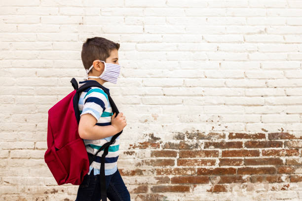 보호 마스크를 들고 학교에 가는 어린 소년 - 교육 뉴스 사진 이미지