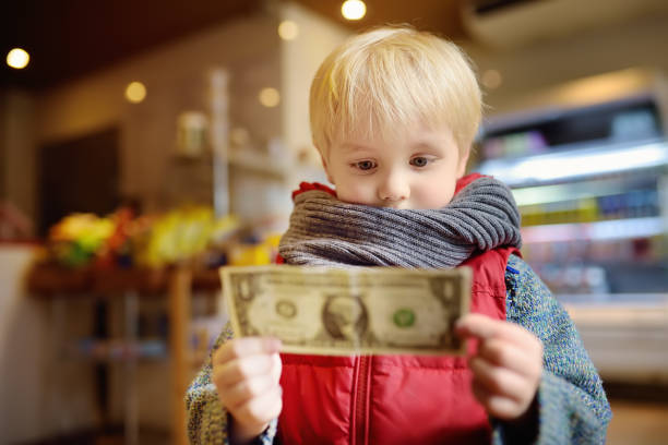 Little boy holds a one-dollar currency note. Little boy holds a one-dollar currency note. Kids and money concept. Training in handling money. allowance stock pictures, royalty-free photos & images
