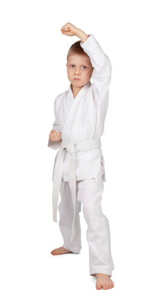 Little boy in kimono stands in karate rack isolated on white stock photo