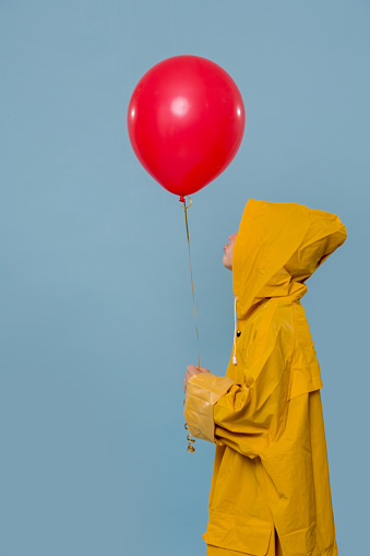 Little Boy In Yellow Raincoat With Red Balloon Over Blue Background ...