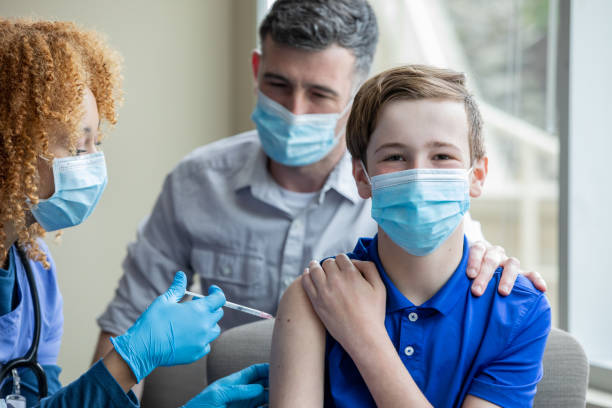 Little boy is finally receiving a COVID-19 vaccine from his pediatrician stock photo