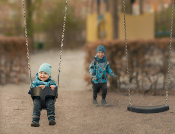 Little boy is swinging at playground, autumn stock photo