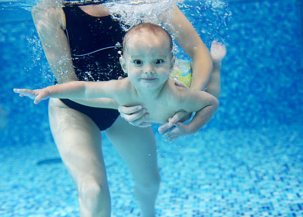 little boy learning to swim in a swimming pool - swimming baby stockfoto's en -beelden