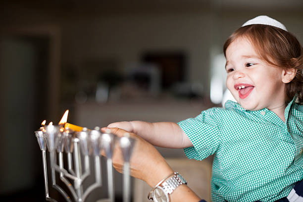 Little boy lighting a silver Menorah stock photo