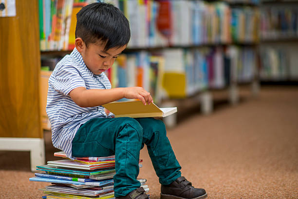 little boy looking at books - child reading imagens e fotografias de stock