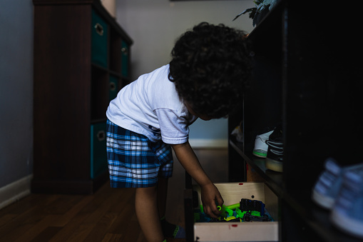 Little boy looking for toys from a toy box in bedroom