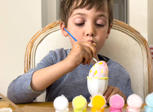 Little boy painting Easter eggs at his home living room Caucasian Little boy painting Easter eggs at his home living room easter sunday stock pictures, royalty-free photos & images