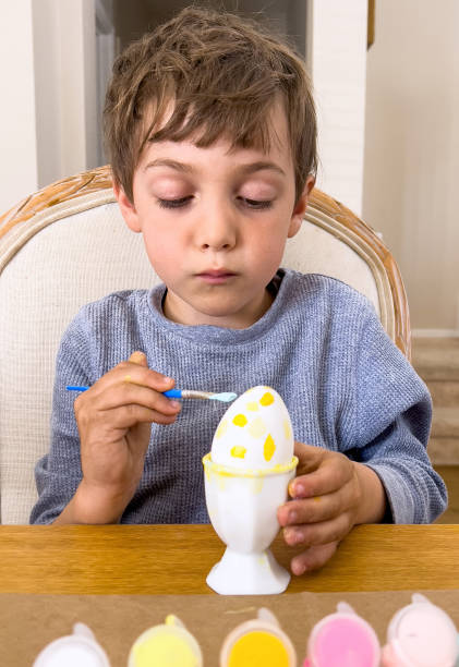 Little boy painting Easter eggs at his home living room Caucasian Little boy painting Easter eggs at his home living room easter sunday stock pictures, royalty-free photos & images