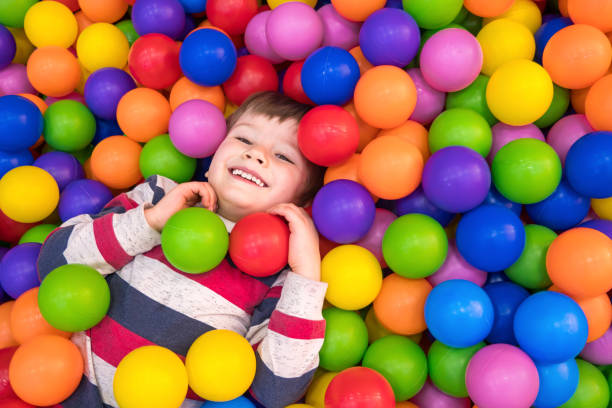 Little boy playing in the pool with plastic balls in the nursery. Indoors activities for children. Development of positive emotions background. Holidays background. Little boy playing in dry pool with plastic balls in the nursery. Close-up leisure activities indoors. Positive emotions background. School holidays. Copy space indoor playground stock pictures, royalty-free photos & images