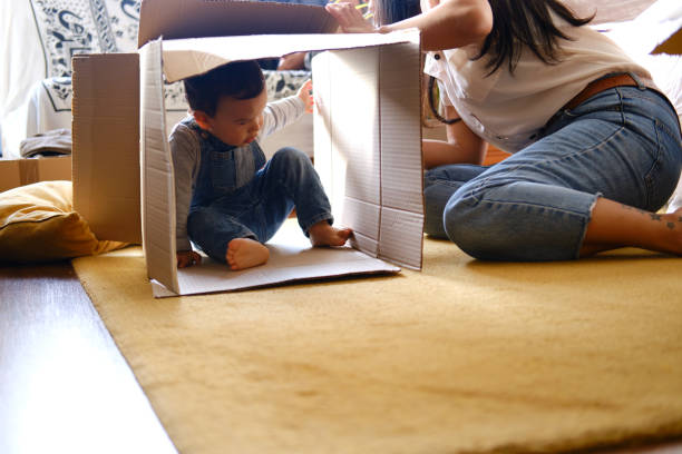 A little boy playing inside a cardboard box in a new apartment. stock photo