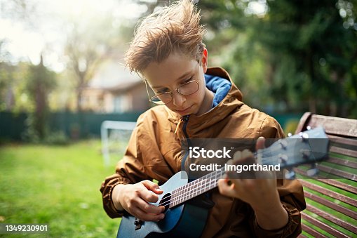 istock Little boy playing ukulele in the backyard. 1349230901