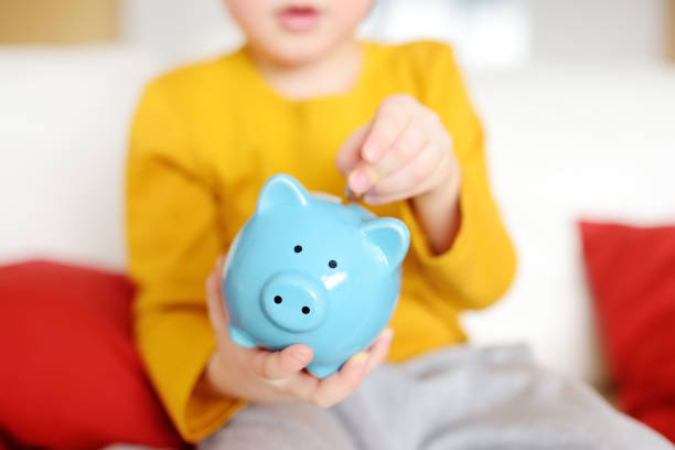 Little boy putting coin into piggy bank Little boy putting coin into piggy bank. Education of children in financial literacy. allowance stock pictures, royalty-free photos & images