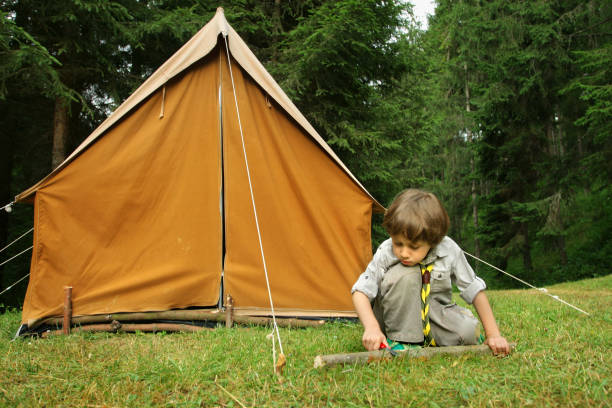 Little Boy Scout building a orange tent Little scout boy boy scout camping stock pictures, royalty-free photos & images