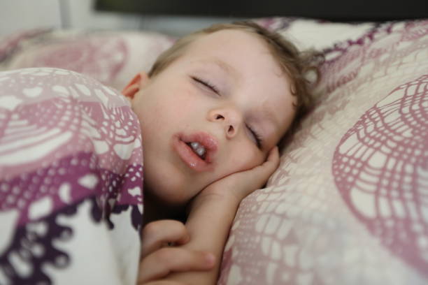 Little boy sleeping in a bed stock photo