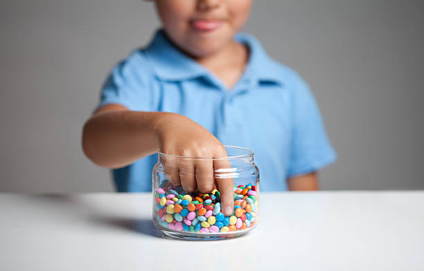 Little boy taking candy from jar stock photo
