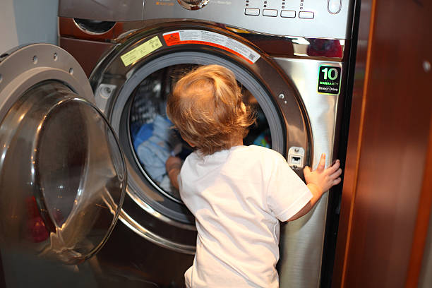 Little boy taking clothes out of a washing machine stock photo