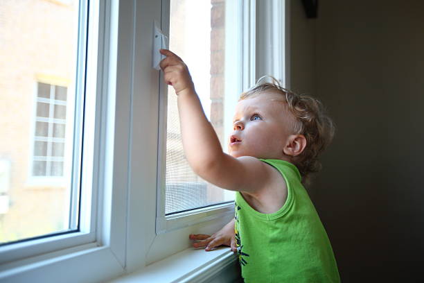 Little boy trying to open the window stock photo