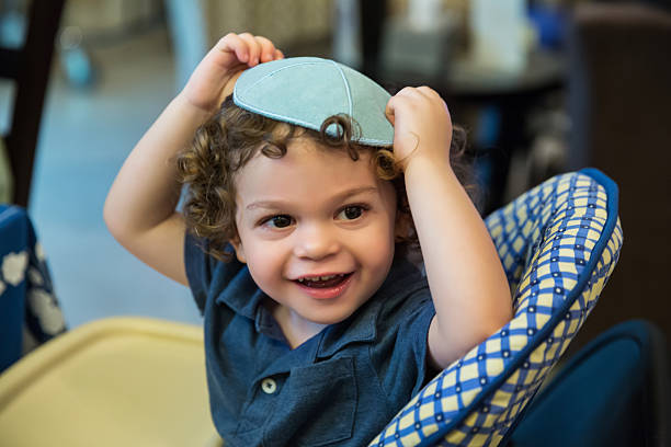 Little boy wearing a yarmulke sits in highchair stock photo