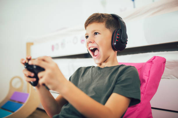 Little boy with gamepad playing video game at home stock photo