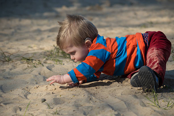 Little boy with haering aid trying to crawl stock photo
