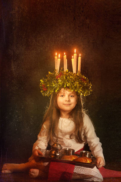 Little caucasian girl in Saint Lucia costume Little caucasian girl in Saint Lucia costume with crown of candles and traditional swedish sweet. Copy space. swedish girl stock pictures, royalty-free photos & images