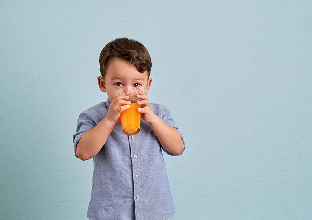 Little child drinking homemade orange juice stock photo