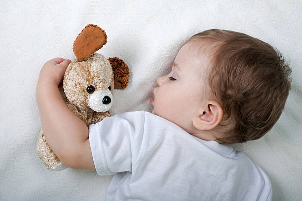 Little child sleeping with teddy bear stock photo