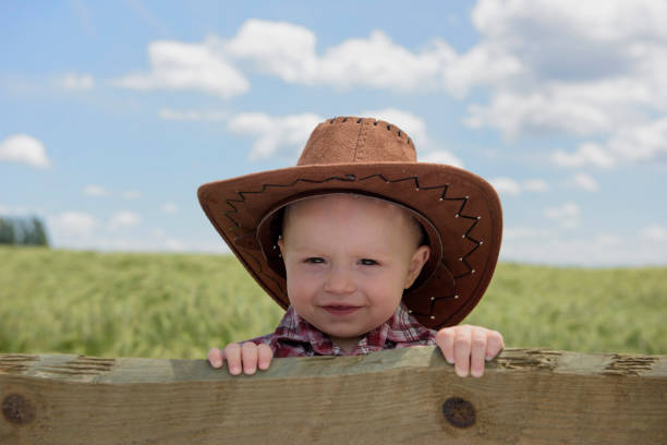 Little cowboy looking over a fence stock photo