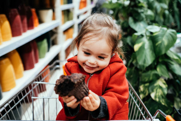 Little Cute Girl Eating Unhealthy Chocolate Cupcake A woman smiles with admiration at her daughter. turkey cupcake cake stock pictures, royalty-free photos & images