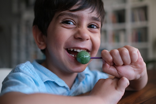 Little cute toddler boy is eating a lollipop candy.